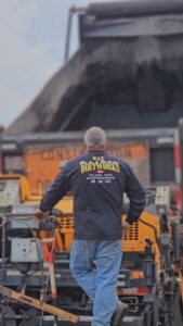 Man standing behind paver, looking over paving work. Join Dirtworks today!